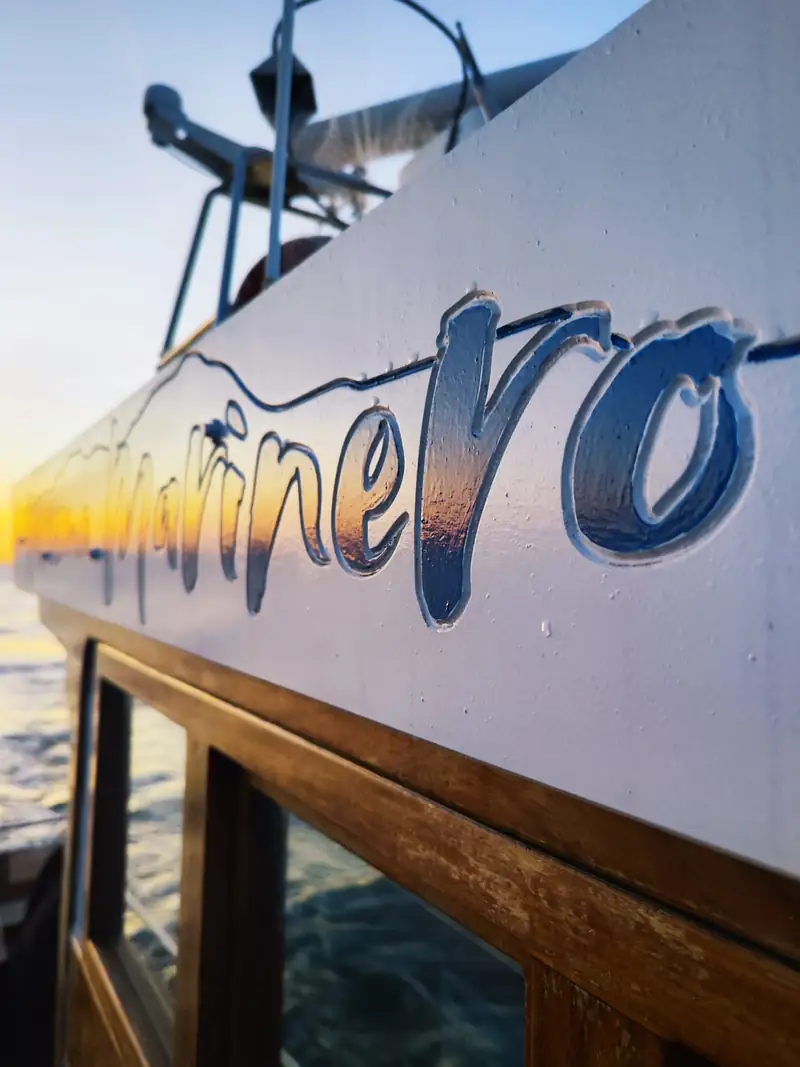 Detalle del casco con el rótulo Turismo Marinero al atardecer