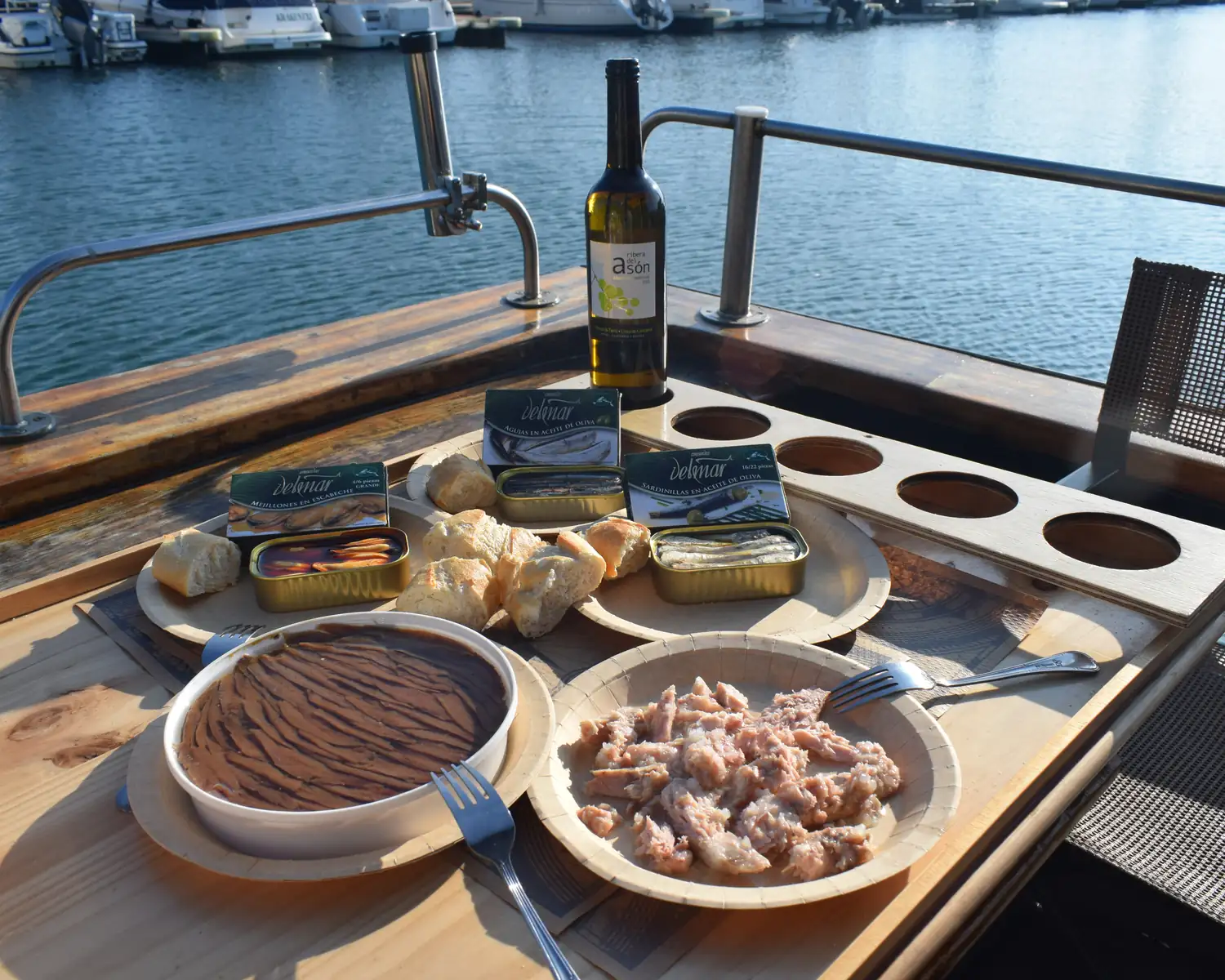 Degustación a bordo: anchoas, bonito, conservas, pan y vino de la tierra sobre la mesa de cubierta